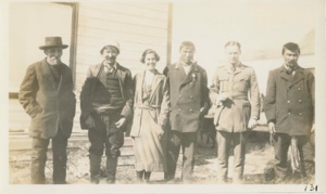 Image of Woman and five men by building